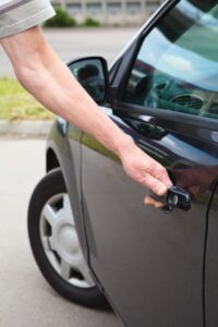 Man trying to open his car door but can't because he is locked out