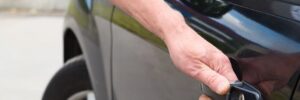 Man trying to open his car door but can't because he is locked out