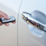 Woman holding a smart key for her car as she pushes it to unlock the door