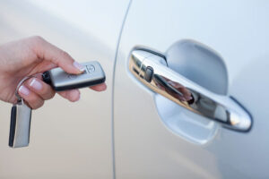 Woman holding a smart key for her car as she pushes it to unlock the door