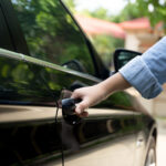 A woman's hand pulling car door handle; she can't get in because she's locked out