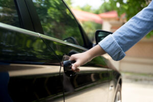 A woman's hand pulling car door handle; she can't get in because she's locked out