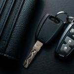 Black leather wallet with car key on a black background
